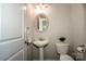 Small half bathroom with pedestal sink, toilet, and decorative oval mirror at 19915 Lamp Lighters Way, Cornelius, NC 28031