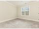 Bright bedroom featuring neutral walls, plush carpeting, and a large window for natural light at 261 Crownsgate Ct, Charlotte, NC 28207