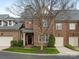 Charming brick townhome with a well-manicured lawn, two-car garage, and mature tree in front at 261 Crownsgate Ct, Charlotte, NC 28207