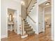 Hallway with wooden floors, staircase with runner, and access to a powder room and other rooms at 261 Crownsgate Ct, Charlotte, NC 28207