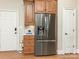 Kitchen features stainless steel refrigerator, wood cabinets and access to white door at 261 Crownsgate Ct, Charlotte, NC 28207