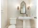 Elegant powder room with pedestal sink, ornate mirror, wall sconces, and modern toilet at 261 Crownsgate Ct, Charlotte, NC 28207