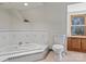 Bright bathroom featuring a tub, toilet, and a window at 265 River Run Rd, Statesville, NC 28625