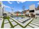 Backyard oasis with a modern pool, fireplace, outdoor kitchen, and lush landscaping for entertaining at 2818 Kenwood Sharon Ln, Charlotte, NC 28211