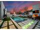Backyard retreat featuring a modern pool, cozy fireplace, and comfortable lounge seating under a vivid sky at 2818 Kenwood Sharon Ln, Charlotte, NC 28211