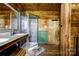 Rustic bathroom featuring wood paneling, a double vanity with granite countertop, and glass enclosed shower at 3640 Oak Haven Ln, Shelby, NC 28150
