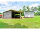 View of two outbuildings, including a barn and shed, set in a sunny and grassy lawn at 3640 Oak Haven Ln, Shelby, NC 28150