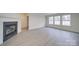 Bright living room with a modern fireplace, light gray floors, and three large windows at 433 Annaberg Ln, Monroe, NC 28110