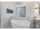 Bathroom featuring marble floors, soaking tub, modern fixtures, and a decorative glass block window at 5231 Lila Wood Cir, Charlotte, NC 28209