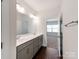 Stylish bathroom featuring a double vanity with gray cabinetry, a large mirror, and an adjoining bedroom at 6332 Kennard Dr, Charlotte, NC 28216