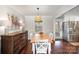 Light-filled dining room featuring hardwood floors, neutral paint, and views into kitchen and living room at 7300 Falkirk Pl, Charlotte, NC 28270
