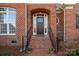 Inviting brick home entrance with arched doorway, black door, and wrought iron railings on brick steps at 8018 Cotton St, Harrisburg, NC 28075