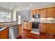 Bright kitchen featuring stainless steel appliances, light wood cabinetry, and stylish backsplash at 8018 Cotton St, Harrisburg, NC 28075