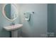 Charming powder room with a pedestal sink, a round mirror, and light blue walls offers a fresh and clean design at 8018 Cotton St, Harrisburg, NC 28075