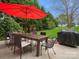 Outdoor patio with a dark wood table, chairs, red umbrella, grill, and backyard views at 809 Circle Trace Rd, Monroe, NC 28110