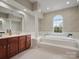 Bright bathroom featuring a large soaking tub, column detail, and double vanity with updated fixtures at 809 Circle Trace Rd, Monroe, NC 28110