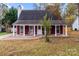 Inviting single-story home features a covered porch with red brick accents and white columns at 8721 Brampton Dr, Charlotte, NC 28215