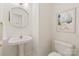 Bright powder room featuring pedestal sink with gold fixtures and round mirror at 9036 Saint Thomas Ln, Charlotte, NC 28277
