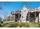 This home features a rear wooden deck, gray siding, and manicured lawns underneath a clear blue sky at 9036 Saint Thomas Ln, Charlotte, NC 28277