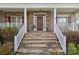 Inviting front porch with stone steps, white railings, and a stylish stone and siding facade at 10823 Caverly Ct, Huntersville, NC 28078