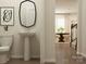 Stylish half bath featuring a pedestal sink and decorative mirror in a well-lit space at 109 Dogwood Grove Pl, Troutman, NC 28166