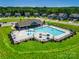 Aerial view of community pool with lounge chairs, umbrellas, and a playground nearby at 109 Dogwood Grove Pl, Troutman, NC 28166