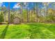 Lush backyard features a large storage shed, a grassy area, mature trees, and a wooden fence at 113 Sandy Cove Ct, Mooresville, NC 28117