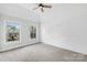 Light-filled bedroom showcases shiplap wall, carpet, ceiling fan, and two windows overlooking a serene outdoor view at 113 Sandy Cove Ct, Mooresville, NC 28117