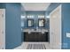 A stylish blue bathroom features a dual vanity with granite countertops and modern fixtures at 17701 Springwinds Dr, Cornelius, NC 28031