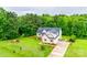 Two-story tan home surrounded by mature trees, lush green lawns and landscaping, a long driveway, and a dark roof at 2050 Sunswept Ln, York, SC 29745