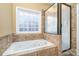 Bright bathroom featuring a jetted tub, shower and natural light from the privacy glass block window at 227 Spicewood Cir, Troutman, NC 28166