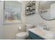 Bright bathroom features a vanity with a round mirror, a shelf, and a toilet by a window for natural light at 3231 Eastwood Dr, Charlotte, NC 28205