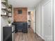 Living room with a red brick accent wall, open doorway to bathroom, and a mini refrigerator at 3231 Eastwood Dr, Charlotte, NC 28205