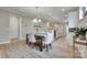 A dining area with an open concept to the kitchen area, hardwood floors, elegant chandelier, and modern table and chairs at 4521 Middlebury Ln, Fort Mill, SC 29715