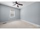 This bedroom features a ceiling fan, neutral carpet, base molding and a bright window at 624 Harris Nw St, Concord, NC 28025