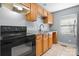 Well-lit kitchen with wooden cabinets, granite countertops, and modern black appliances at 624 Harris Nw St, Concord, NC 28025