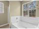 A bright primary bathroom featuring a large window and a soaking tub at 8932 Raven Park Dr, Charlotte, NC 28216