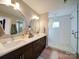 Modern bathroom with dual sinks, vanity, and glass shower stall at 1207 Lakedell Dr, Charlotte, NC 28215