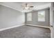 Spacious bedroom with gray walls, carpet, a ceiling fan, and windows with views of the outdoors at 125 Arrow Point Ln, Davidson, NC 28036