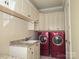 Bright laundry room featuring red washer and dryer, ample storage, counter space and basin sink at 134 Larkhaven Ln, Mooresville, NC 28117