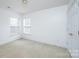 Sunlit carpeted room with two windows, a neutral color palette, and a white door with brass hardware at 1991 9Th Street Se Pl, Hickory, NC 28602