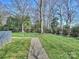 Well-maintained backyard with manicured lawn, mature trees, and a charming stone pathway leading to a seating area at 2423 Lemon Tree Ln, Charlotte, NC 28211