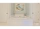Bright bathroom with a large soaking tub with marble trim and an elegant piece of artwork at 2423 Lemon Tree Ln, Charlotte, NC 28211