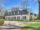 Charming white home featuring a gray roof, dormer windows, and a spacious driveway with lush greenery at 2423 Lemon Tree Ln, Charlotte, NC 28211
