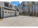 The garage is a three car garage with a big concrete driveway surrounded by beautiful green trees at 2615 Farm House Ln, Monroe, NC 28110