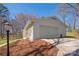 A stand alone garage with a white painted brick facade and a large garage door with a driveway and surrounding landscaping at 534 Kirby Ln, Matthews, NC 28104