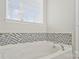 Close-up of a large bathtub, with black and white tile, and a window with blinds at 571 Rough Hewn Ln, Rock Hill, SC 29730