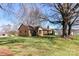 Spacious lawn surrounds this brick single-story home shaded by beautiful mature trees on a sunny day at 7770 Sherrills Ford Rd, Sherrills Ford, NC 28673