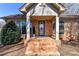 Close-up of brick front porch with decorative glass door, flanked by large windows and trimmed shrubs at 7770 Sherrills Ford Rd, Sherrills Ford, NC 28673