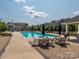 Community pool with lounge chairs, tables and umbrellas surrounded by residential buildings at 832 Imperial Ct, Charlotte, NC 28273